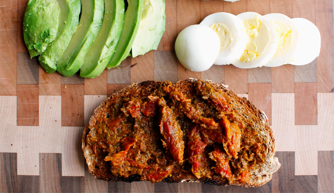 Toast topped with sundried tomato paste, avocado slices, and a sliced hard boiled egg