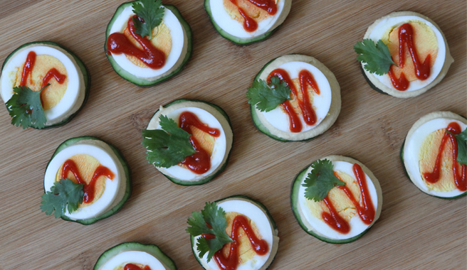 Cucumber slices topped with sliced hard cooked eggs and sriracha
